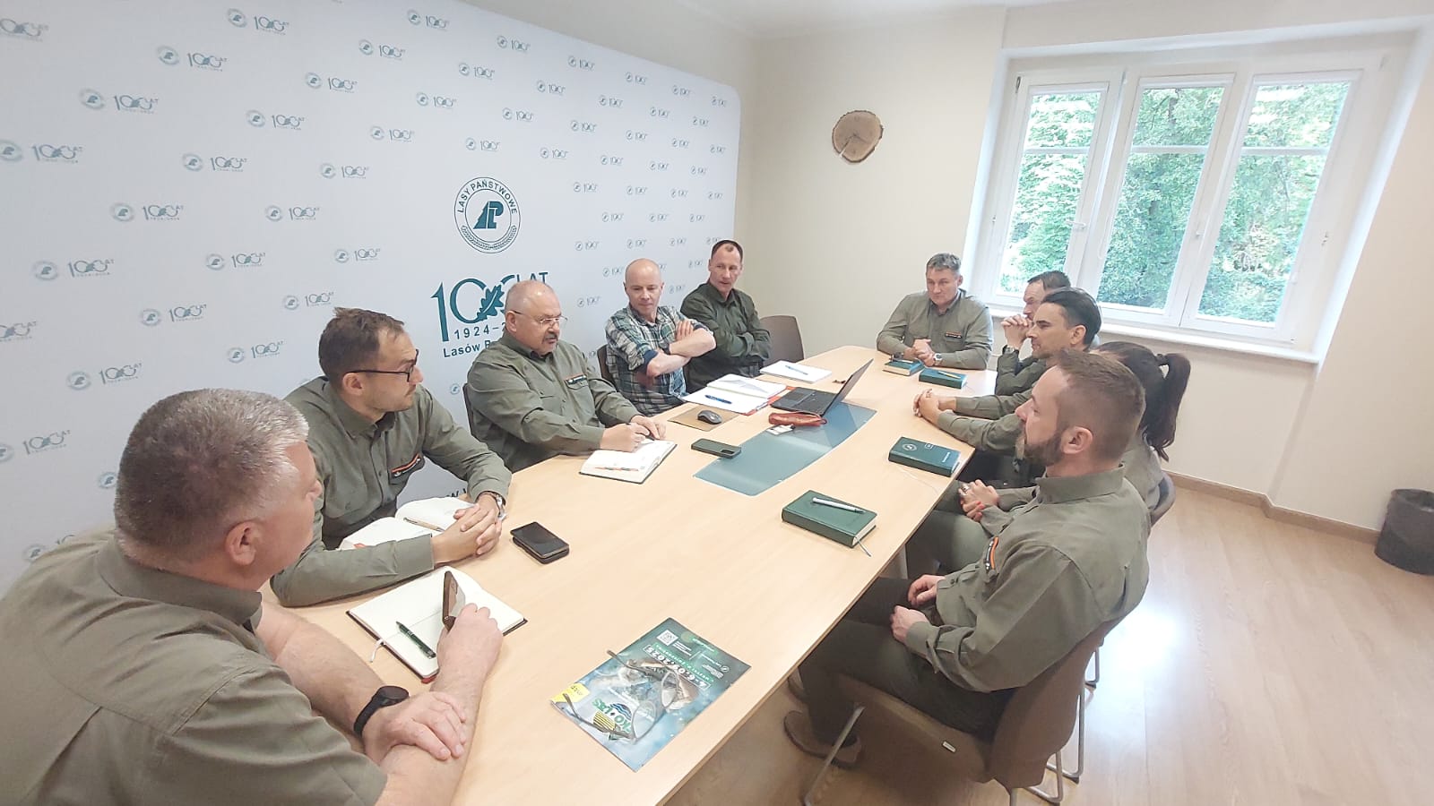 Zdjęcie przedstawia grupę osób w salce konferencyjnej RDLP w Poznaniu siedzących przy stole, pracownicy dyrekcji w zielonych mundurowych koszulach. Fot. M. Kowalkowska (RDLP w Poznaniu)