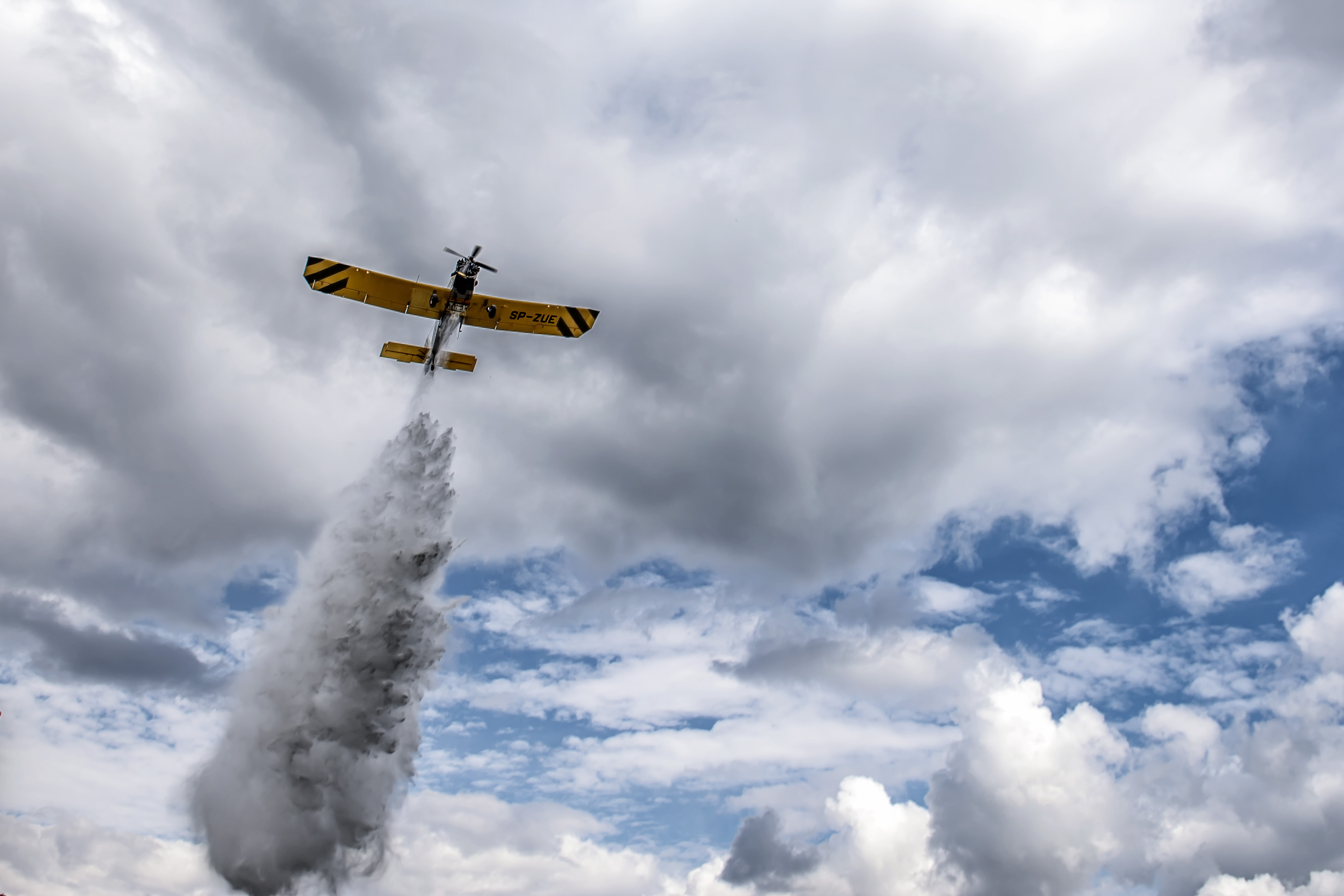 Żółty samolot ze śmigłem na przedzie zrzuca wodę na tle nieba. Fot. Archiwum Lasy Państwowe