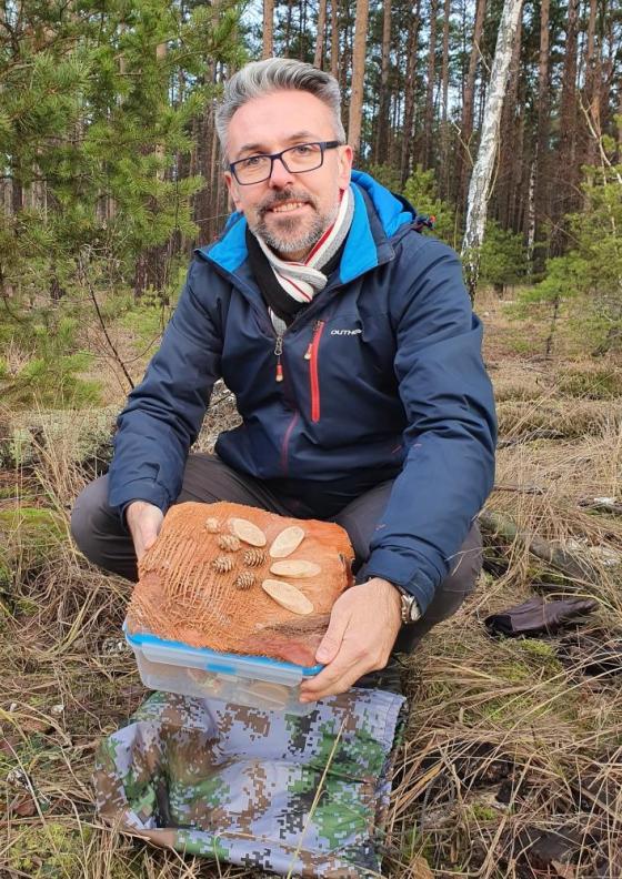 Fotografia przedstawia Zastępcę Nadleśniczego Nadleśnictwa Oborniki prezentującego jedną ze skrytek. Archiwum Nadleśnictwa Oborniki.