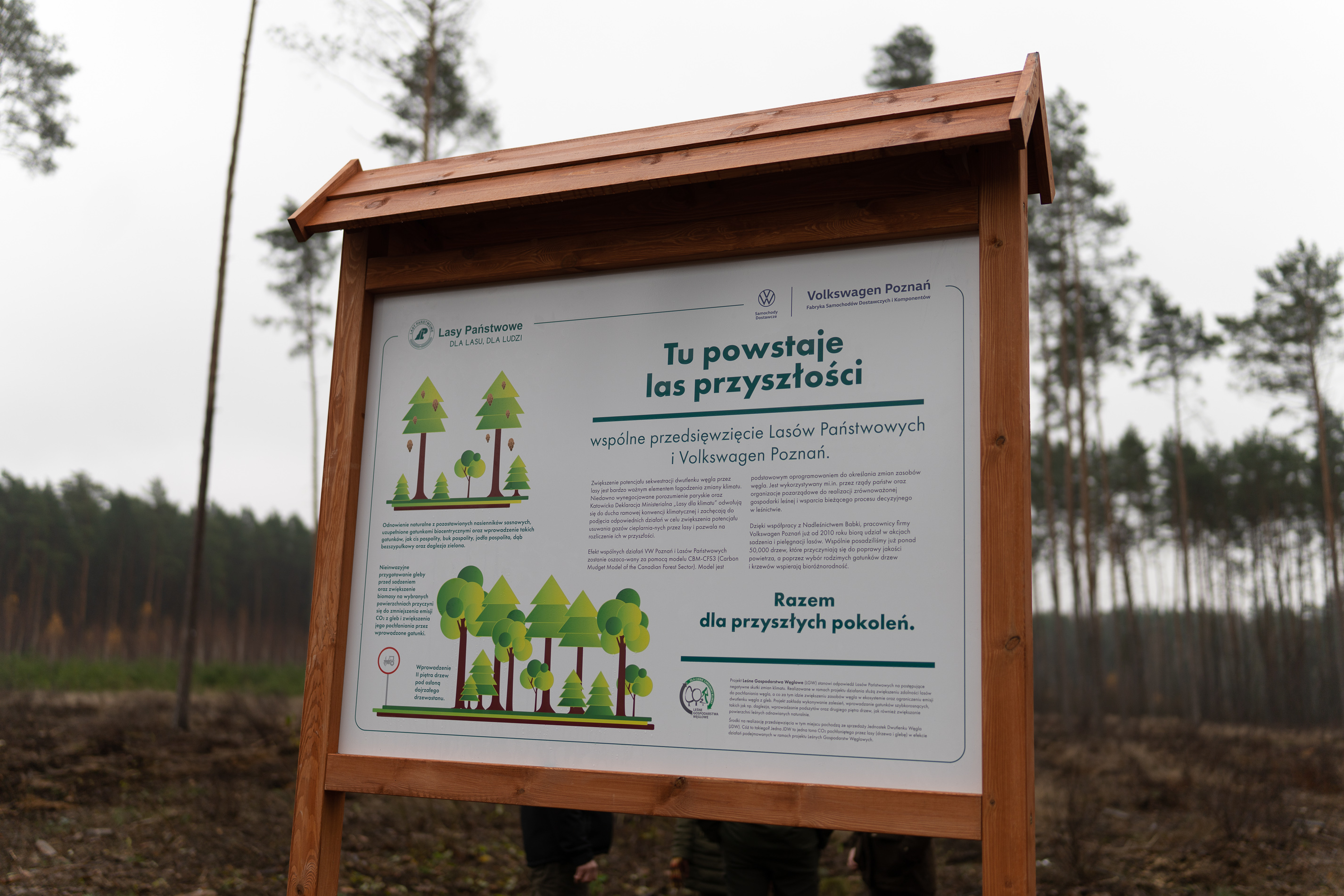 Fotografia przedstawia tablicę informacyjną podstawioną w miejscu zasadzenia Lasu Przyszłości. Fot. VW Poznań