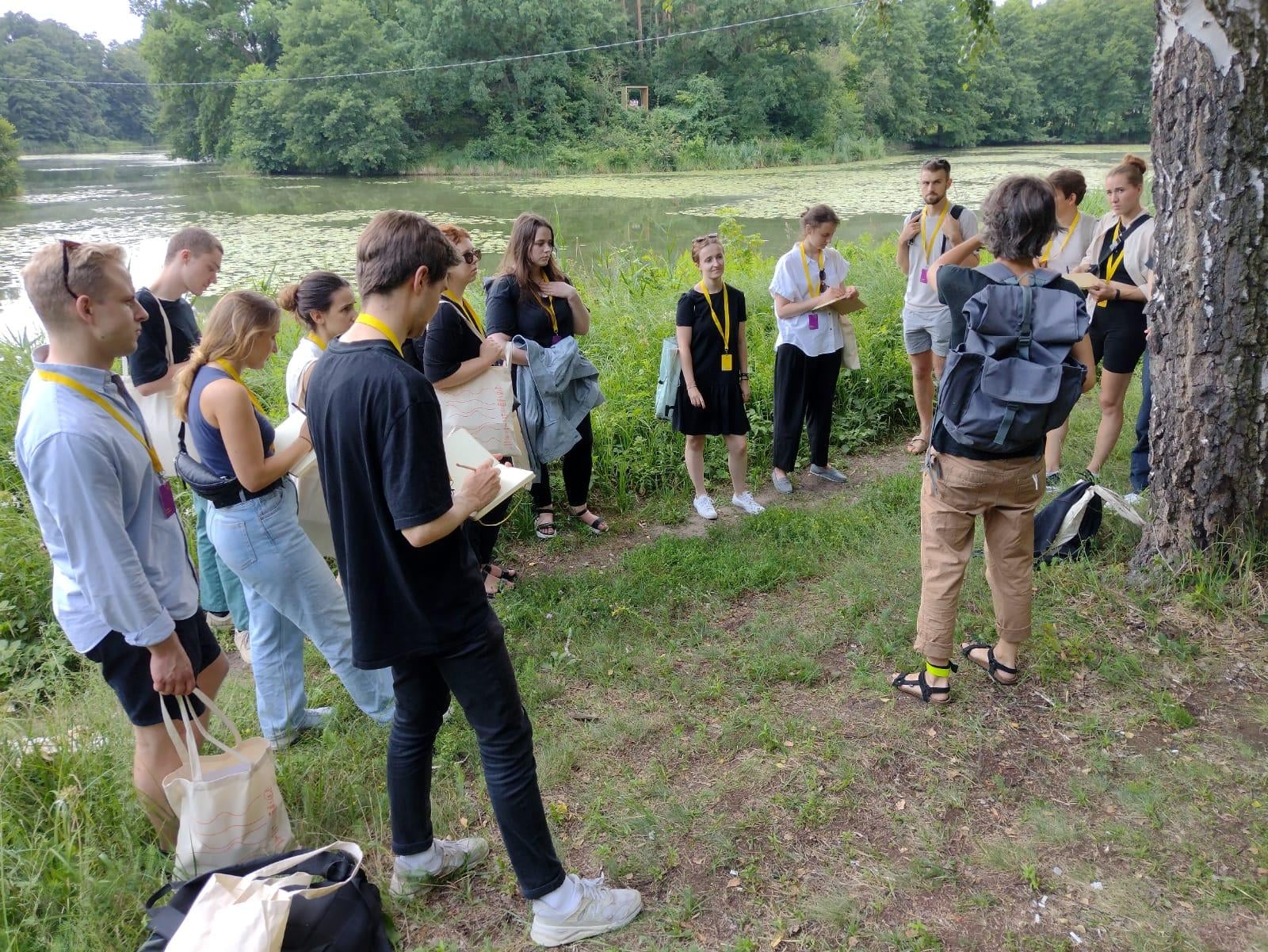 Fotografia przedstawia uczestników warsztatów Mood for wood słuchających prelekcji w terenie. Fot. Daniel Grzybowski