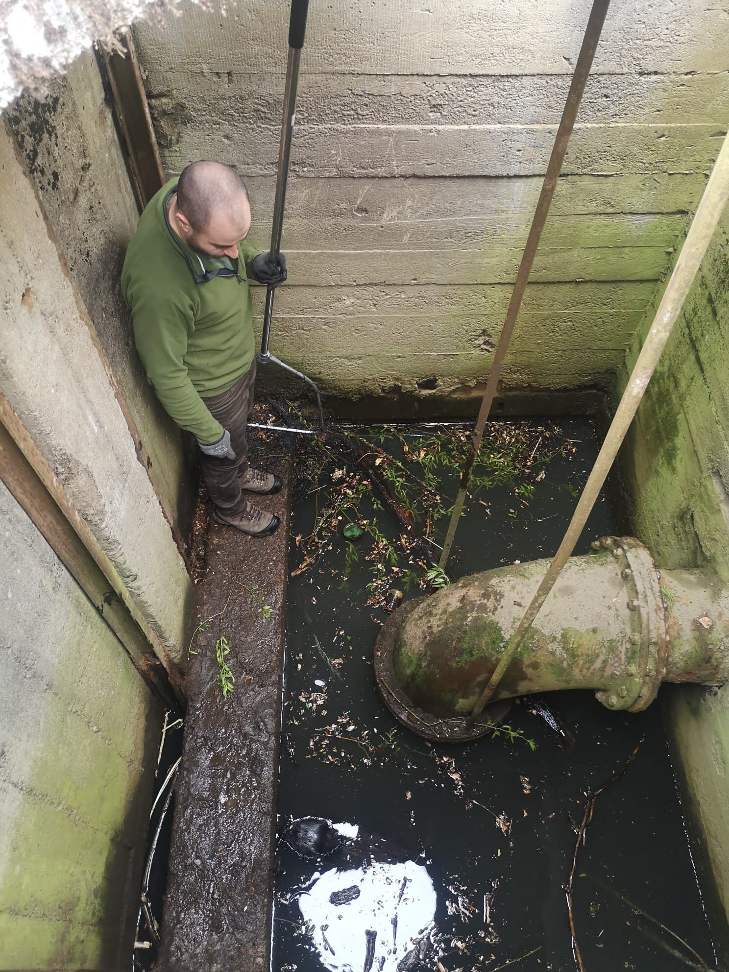 Zdjęcie przedstawia wnętrze zbiornika, w którym został uwięziony bóbr i stojącego wewnątrz człowieka. Fot. Marek Dobroczyński (Nadleśnictwo Jarocin)