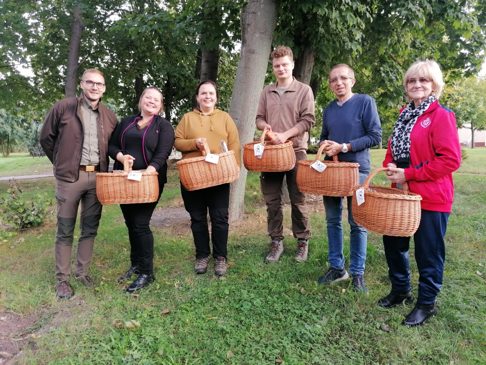 Zdjecie przedstawia grupę 6 osób trzymających w rękach duże wiklinowe kosze i stojących na tle drzew. Fot. Archiwum RDLP w Poznaniu.