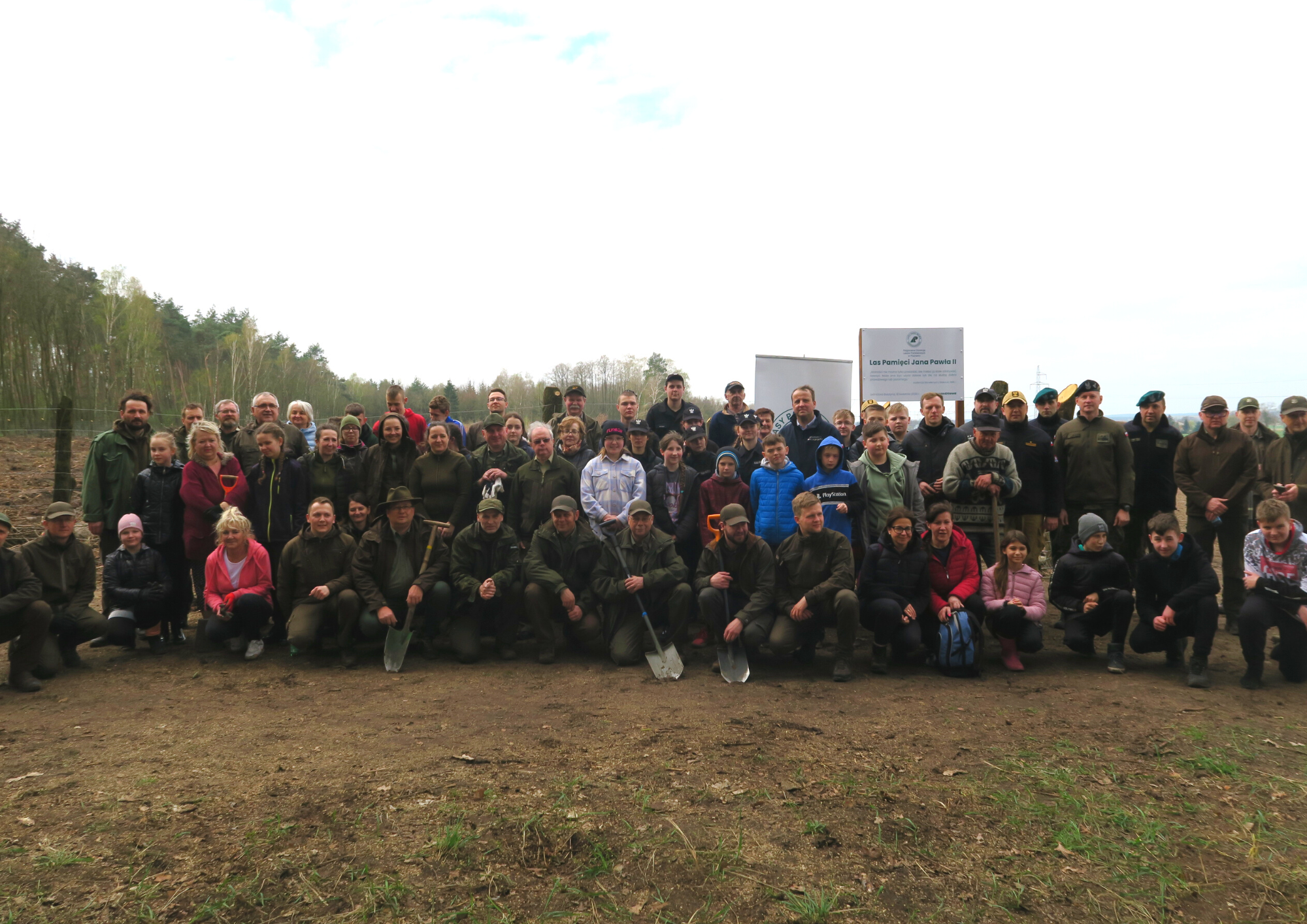 Zdjęcie przedstawia grupę kilkudziesięciu osób m.in. uczniów, żołnierzy, leśników, stojących przy powierzchni, na której posadzili sadzonki dębów. Fot. RDLP w Poznaniu