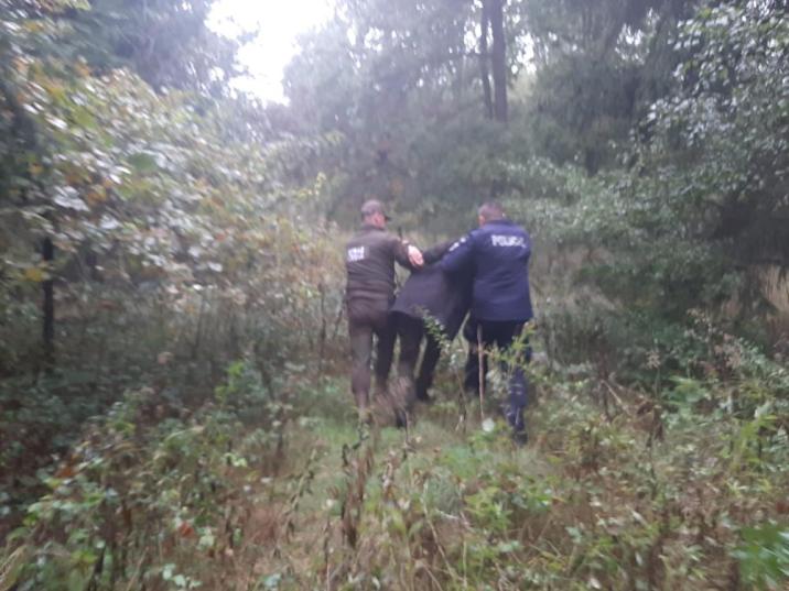 Zdjęcie&#x20;przedstawia&#x20;kłusownika&#x20;prowadzonego&#x20;w&#x20;lesie&#x20;przez&#x20;funkcjonariuszy&#x20;policji&#x20;i&#x20;straży&#x20;leśnej&#x2e;&#x20;Fot&#x2e;&#x20;Państwowa&#x20;Straż&#x20;Łowiecka